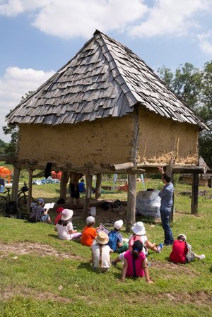 bâtiment en bois surélevé avec des enfants écoutant un guide devant.